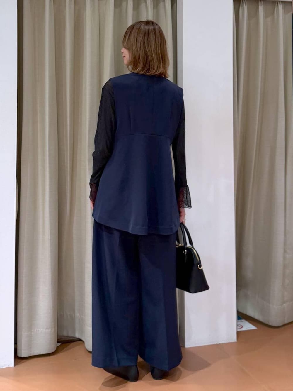 ブラック系のハンドバッグ、ブラック系のパンプス、ブラック系のTシャツ/カットソーを着用したレディースの冬コーディネートの4枚目の写真