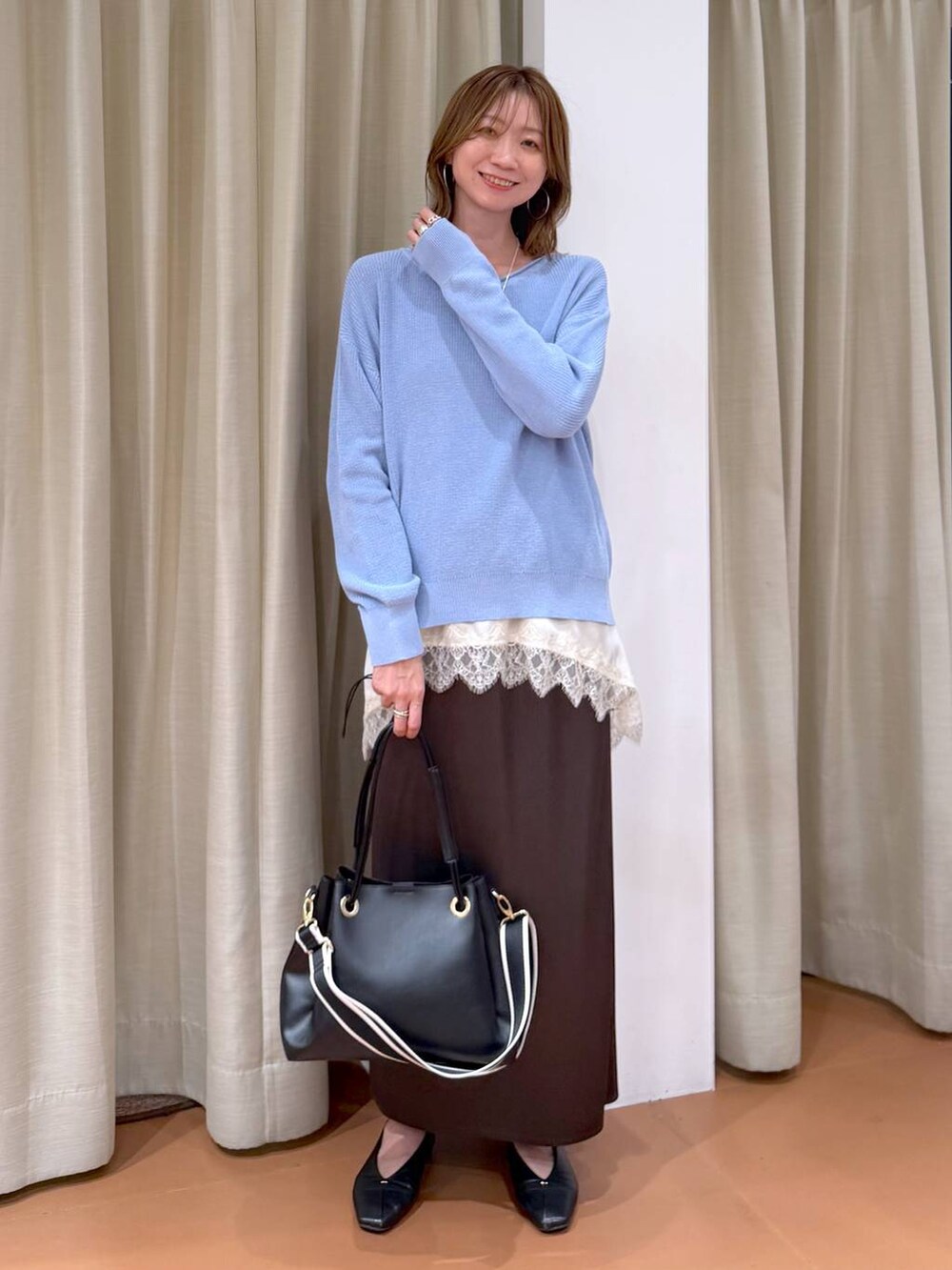 ブルー系のニット/セーター、ブラック系のパンプス、ブラウン系のスカートを着用したレディースの春コーディネートの6枚目の写真