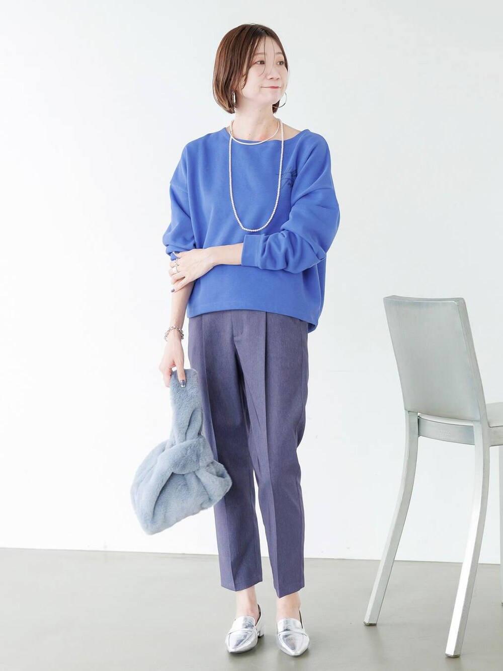 シルバー系のローファー、ブルー系のデニムパンツを着用したレディースの秋コーディネートの2枚目の写真