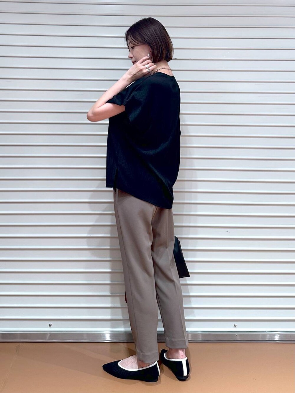 ブラック系のパンプス、ブラック系のショルダーバッグ、シルバー系のネックレスを着用したレディースの夏コーディネートの3枚目の写真