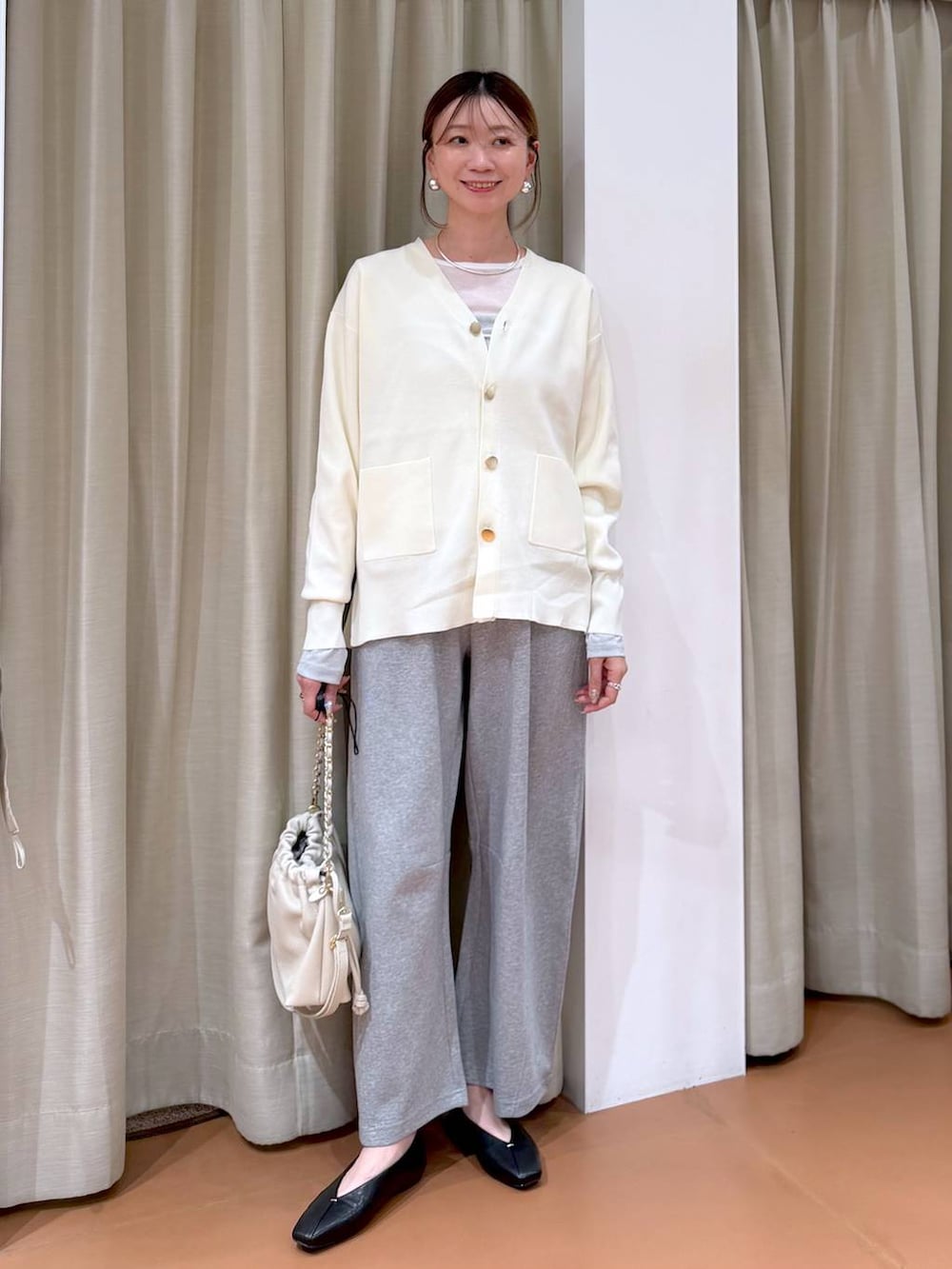 ホワイト系のカーディガン/ボレロ、ホワイト系のハンドバッグ、ブラック系のパンプスを着用したレディースの冬コーディネートの2枚目の写真