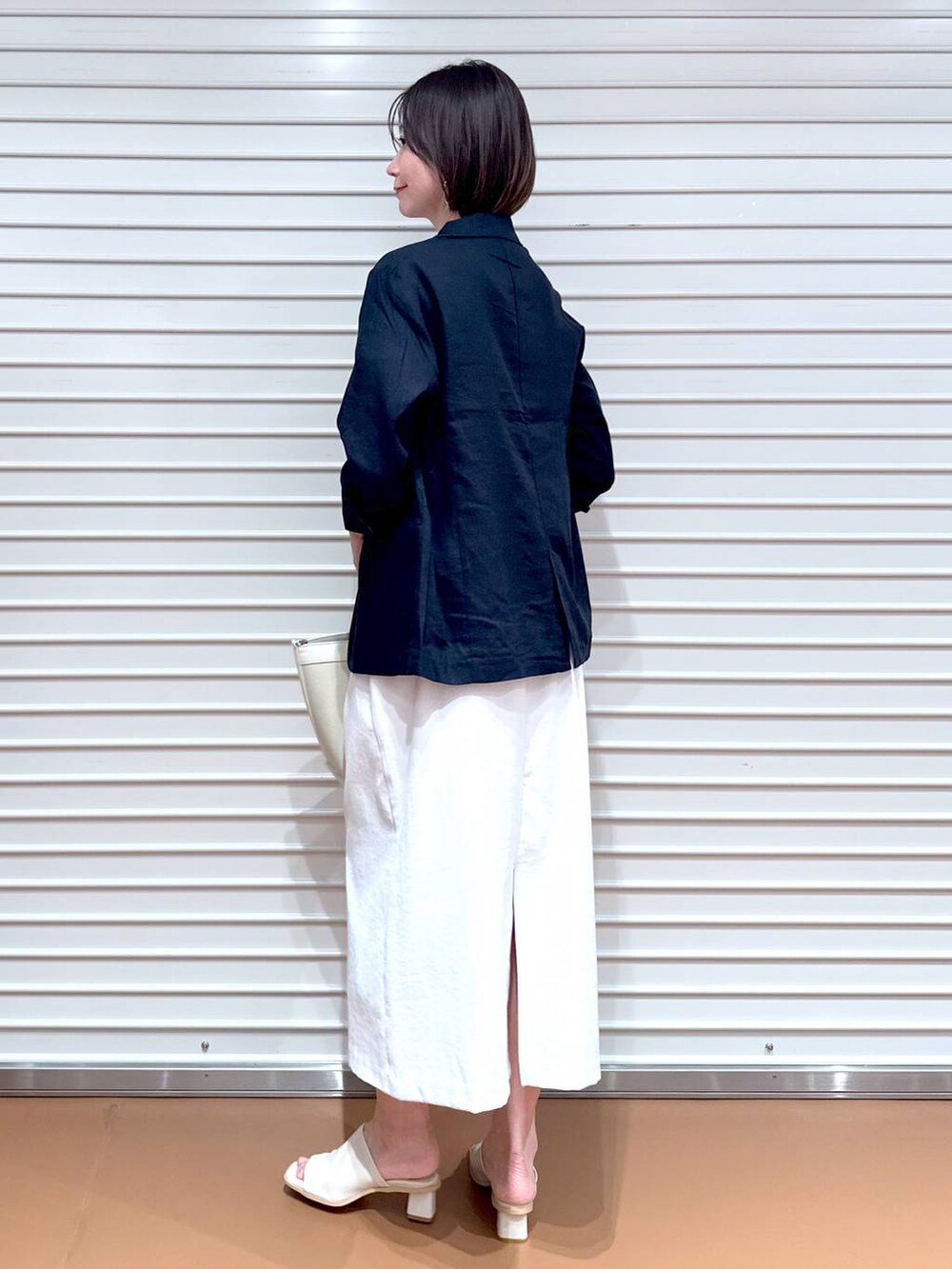 ホワイト系のサンダル、ホワイト系のトートバッグ、グレー系のスカートを着用したレディースの秋コーディネートの4枚目の写真