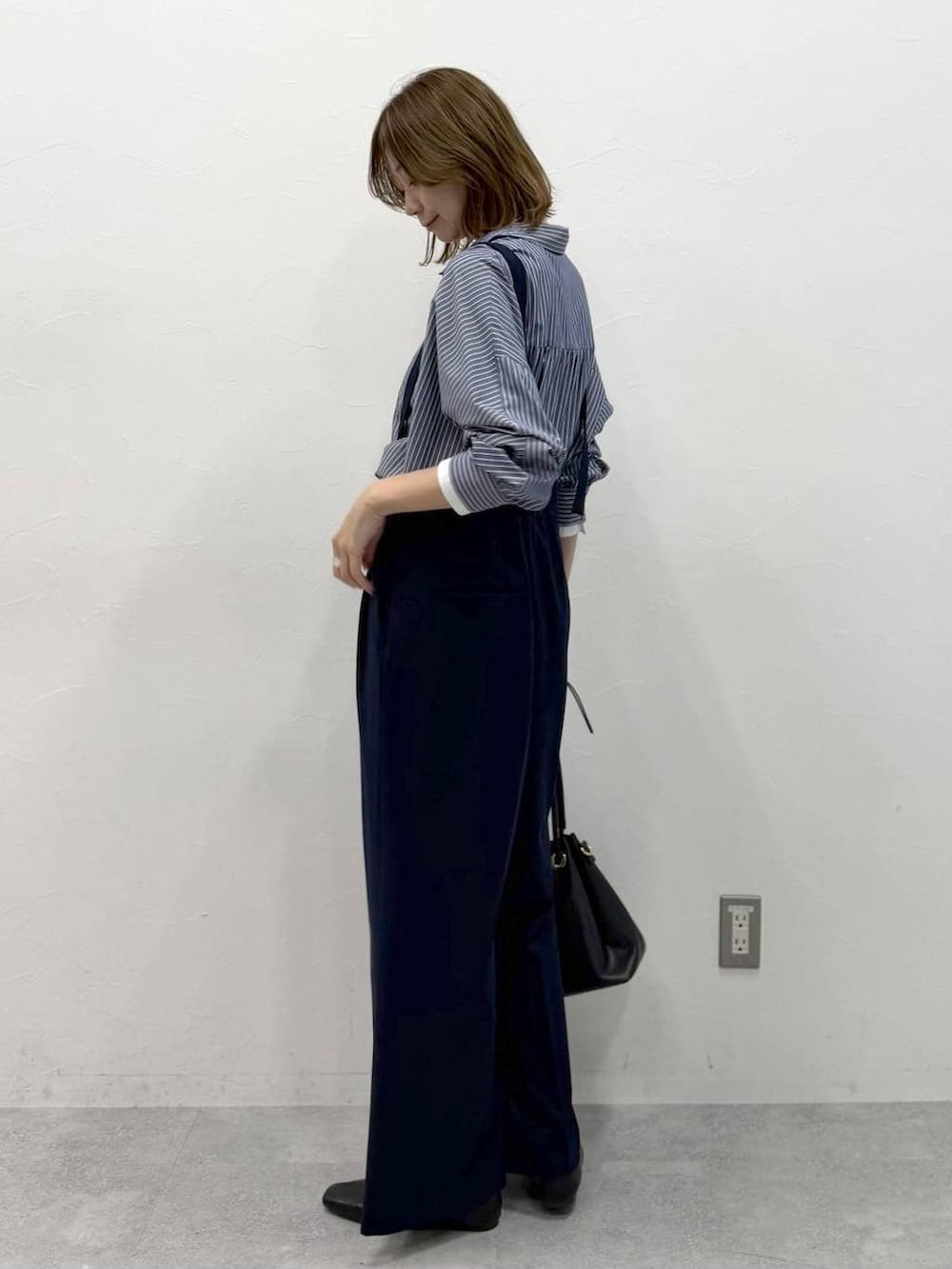 ブラック系のパンプス、ホワイト系のシャツ/ブラウス、グレー系のサロペット/オーバーオールを着用したレディースの春コーディネートの4枚目の写真