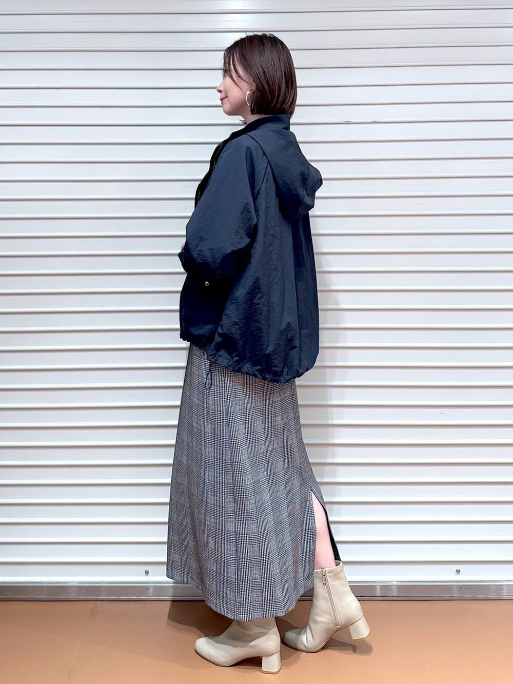 ブラック系のスカート、ブラウン系のTシャツ/カットソー、ブルー系のマウンテンパーカーを着用したレディースの秋コーディネートの4枚目の写真