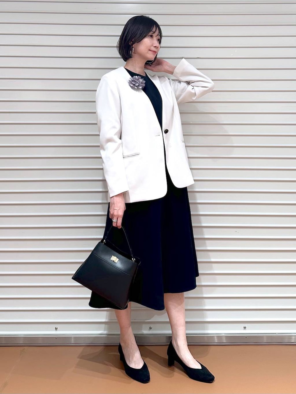 ベージュ系のノーカラージャケット、ブルー系のワンピース、ブラック系のハンドバッグを着用したレディースの冬コーディネートの2枚目の写真