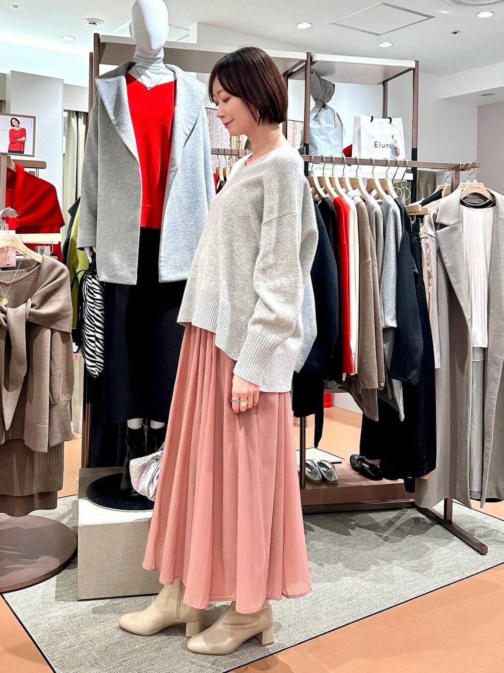 グレー系のニット/セーター、ベージュ系のブーツ、ピンク系のスカートを着用したレディースの冬コーディネートの3枚目の写真