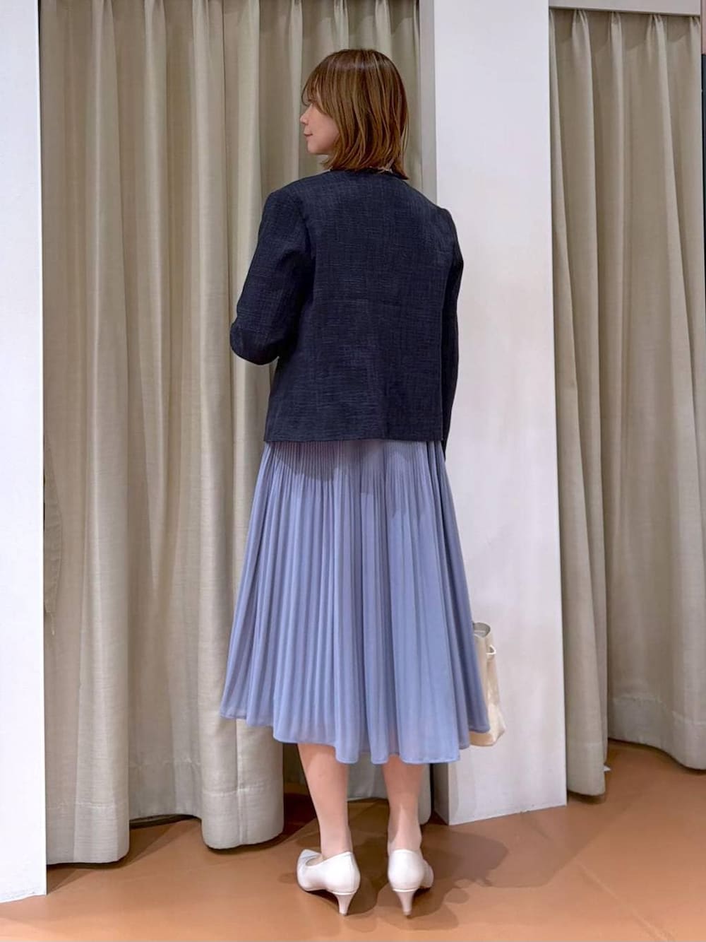 ベージュ系のパンプス、ブルー系のノーカラージャケット、ブルー系のワンピースを着用したレディースの冬コーディネートの4枚目の写真