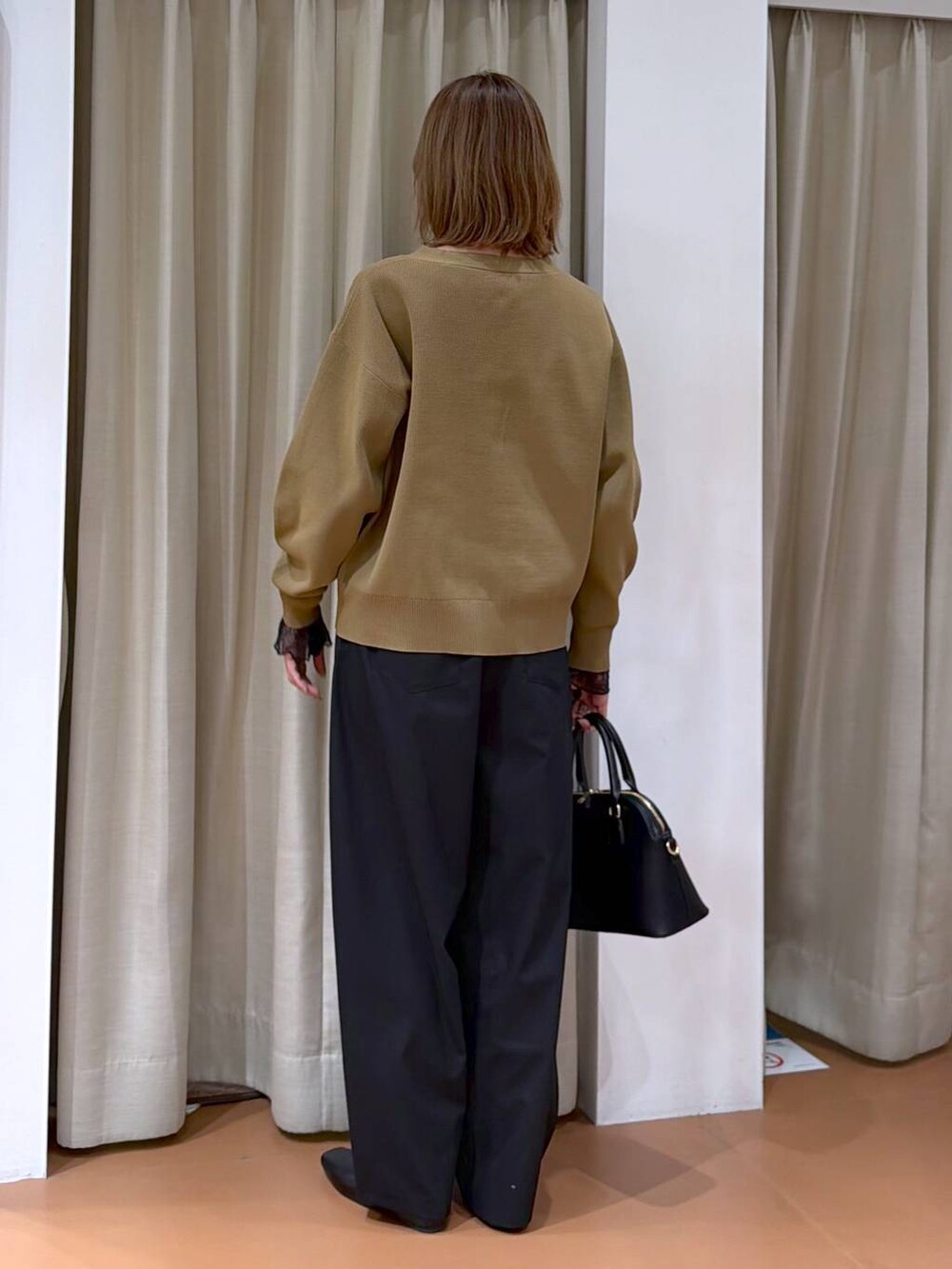 ブラック系のハンドバッグ、ブラック系のパンプス、ブラック系のTシャツ/カットソーを着用したレディースの冬コーディネートの4枚目の写真