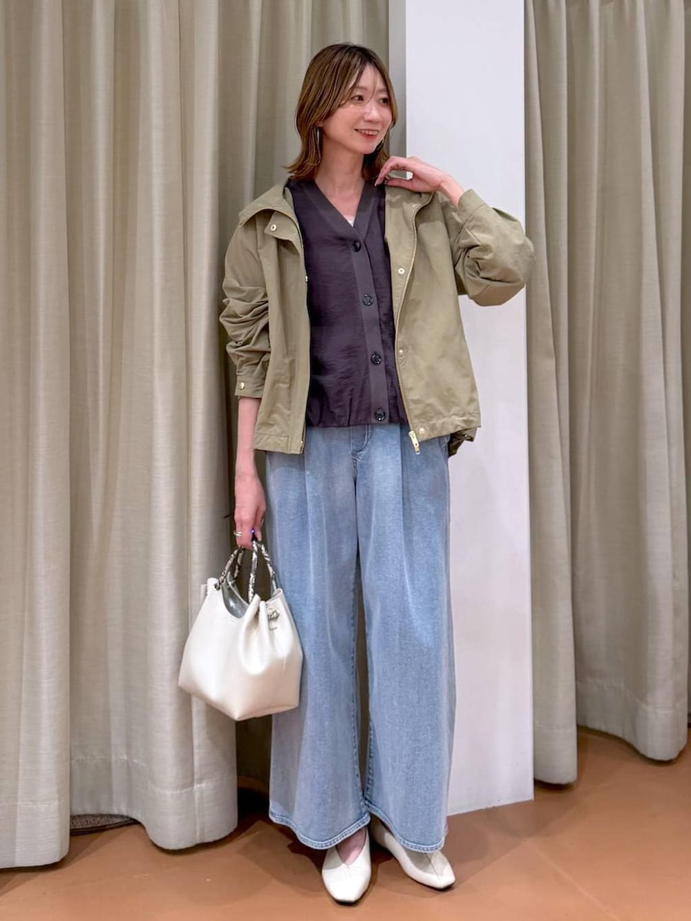 ホワイト系のパンプス、ブルー系のデニムパンツ、ホワイト系のハンドバッグを着用したレディースの春コーディネートの2枚目の写真