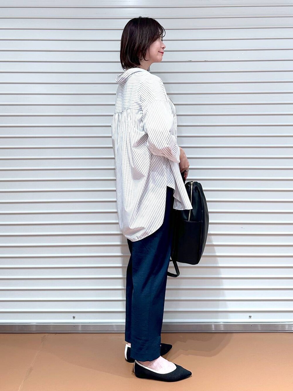 ブラック系のパンプス、ホワイト系のシャツ/ブラウス、ブラック系のバックパック/リュックを着用したレディースの春コーディネートの3枚目の写真