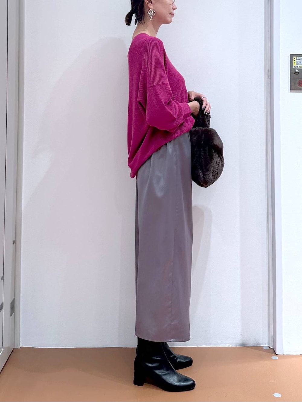 ピンク系のニット/セーター、グレー系のスカート、ブラック系のブーツを着用したレディースの秋コーディネートの6枚目の写真