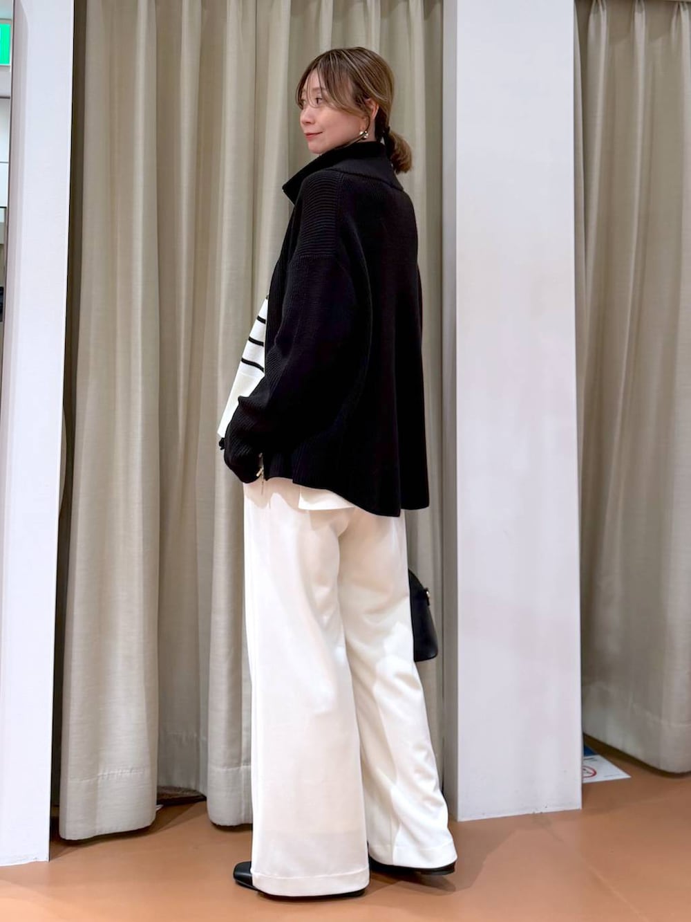 ホワイト系のニット/セーター、ブラック系のカーディガン/ボレロ、ブラック系のハンドバッグを着用したレディースの冬コーディネートの5枚目の写真