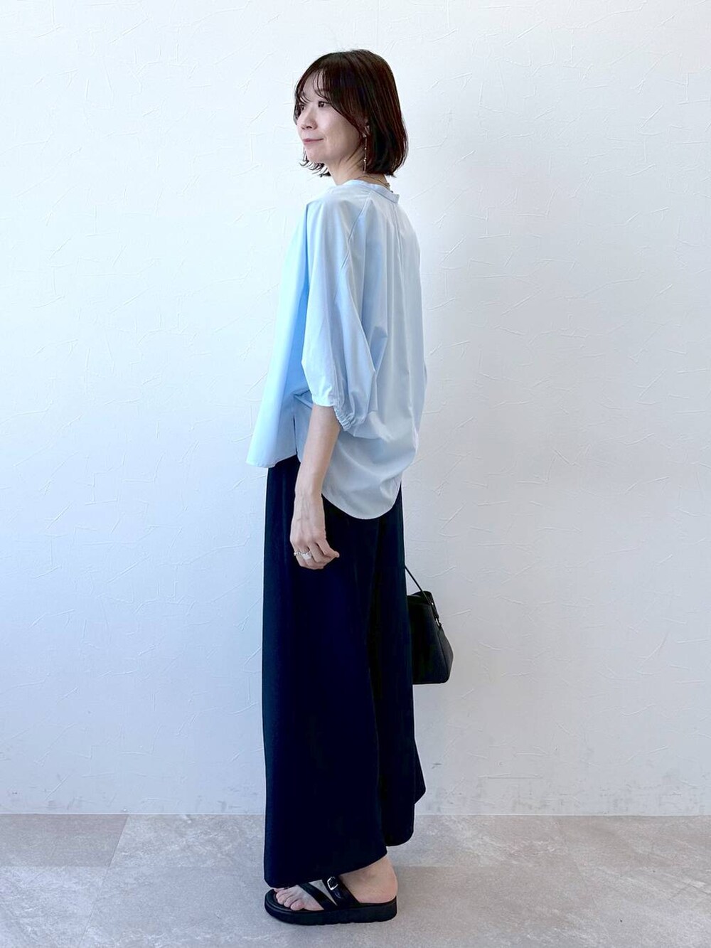 ブラック系のサンダル、ブルー系のシャツ/ブラウス、ブラック系のハンドバッグを着用したレディースの夏コーディネートの3枚目の写真