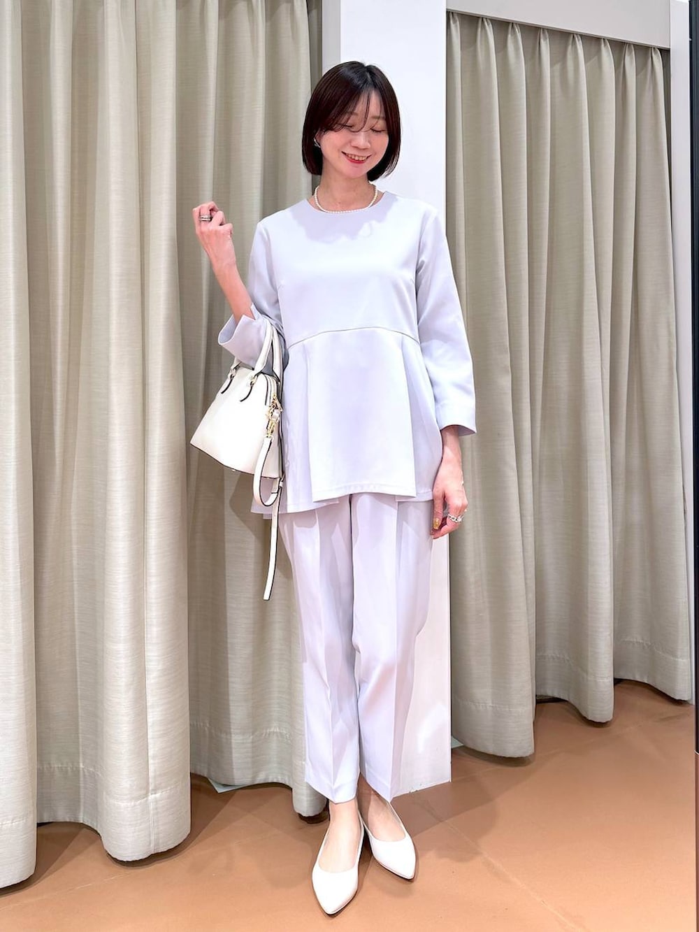 ブルー系のスーツパンツ、ブルー系のシャツ/ブラウス、ホワイト系のハンドバッグを着用したレディースの冬コーディネートの2枚目の写真