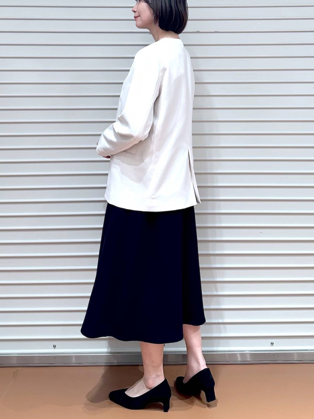 ベージュ系のノーカラージャケット、ブルー系のワンピース、ブラック系のハンドバッグを着用したレディースの冬コーディネートの6枚目の写真