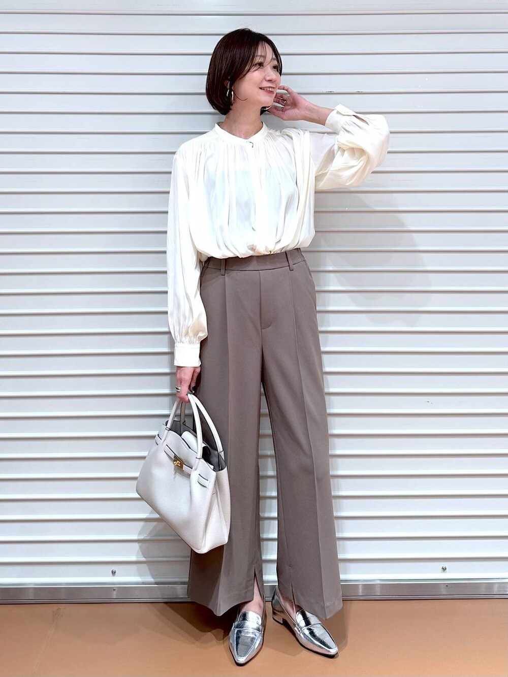 ブラウン系のその他パンツ、グレー系のカーディガン/ボレロ、グレー系のハンドバッグを着用したレディースの秋コーディネートの2枚目の写真