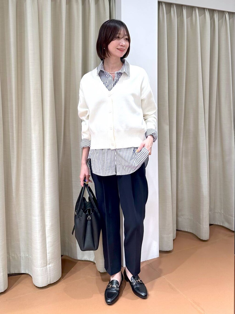 ブラック系のローファー、ブルー系のスーツパンツ、ブラック系のハンドバッグを着用したレディースの冬コーディネートの2枚目の写真