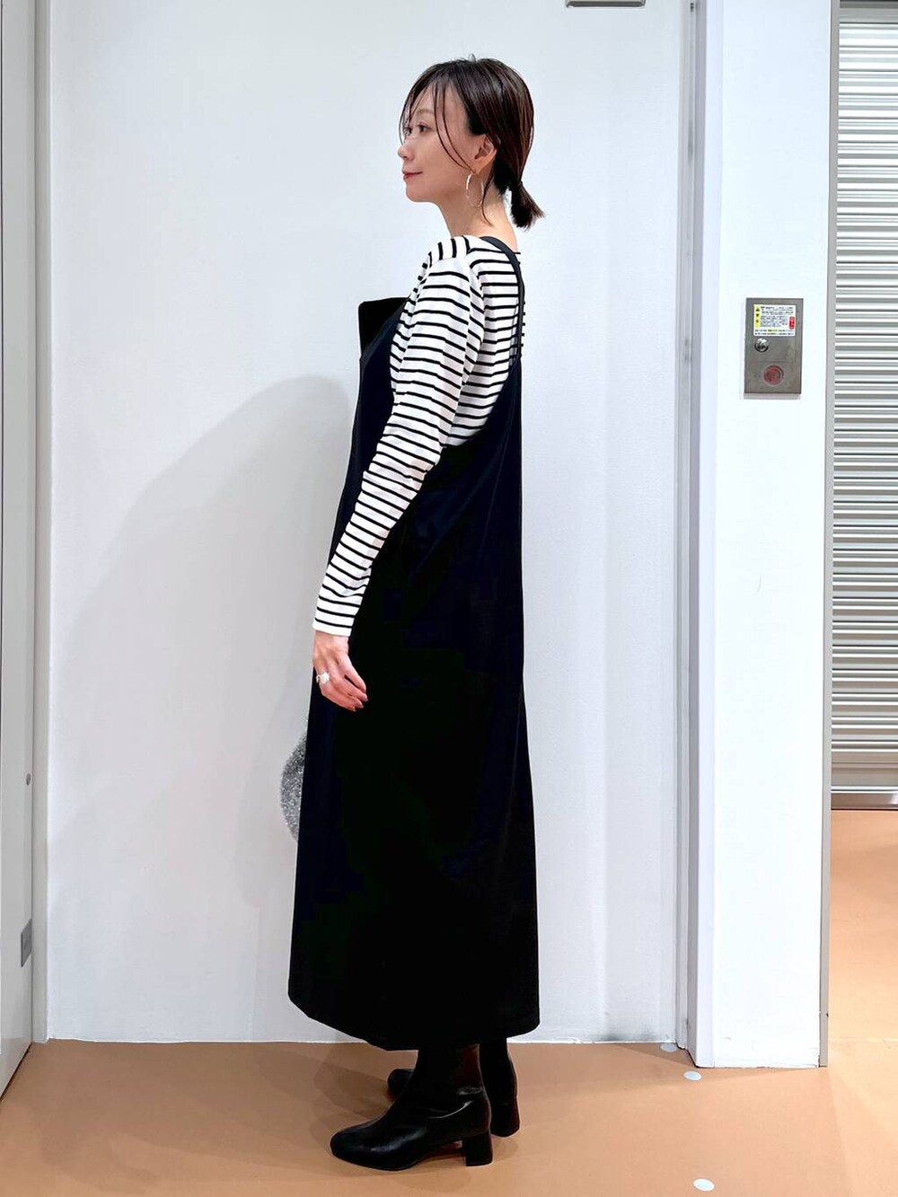 ブラック系のニット/セーター、ブラック系のブーツ、シルバー系のハンドバッグを着用したレディースの秋コーディネートの3枚目の写真