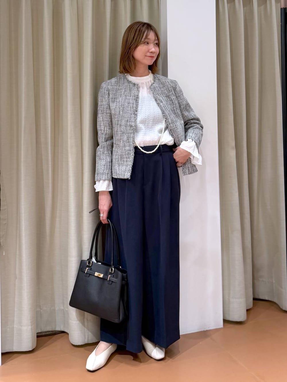 ホワイト系のパンプス、ホワイト系のシャツ/ブラウス、ブラック系のノーカラージャケットを着用したレディースの冬コーディネートの2枚目の写真