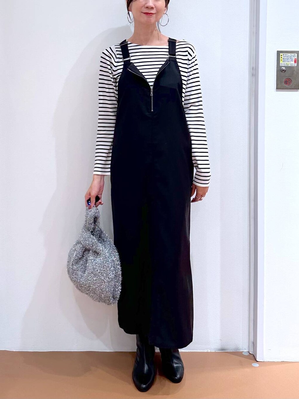 ブラック系のニット/セーター、ブラック系のブーツ、シルバー系のハンドバッグを着用したレディースの秋コーディネートの5枚目の写真