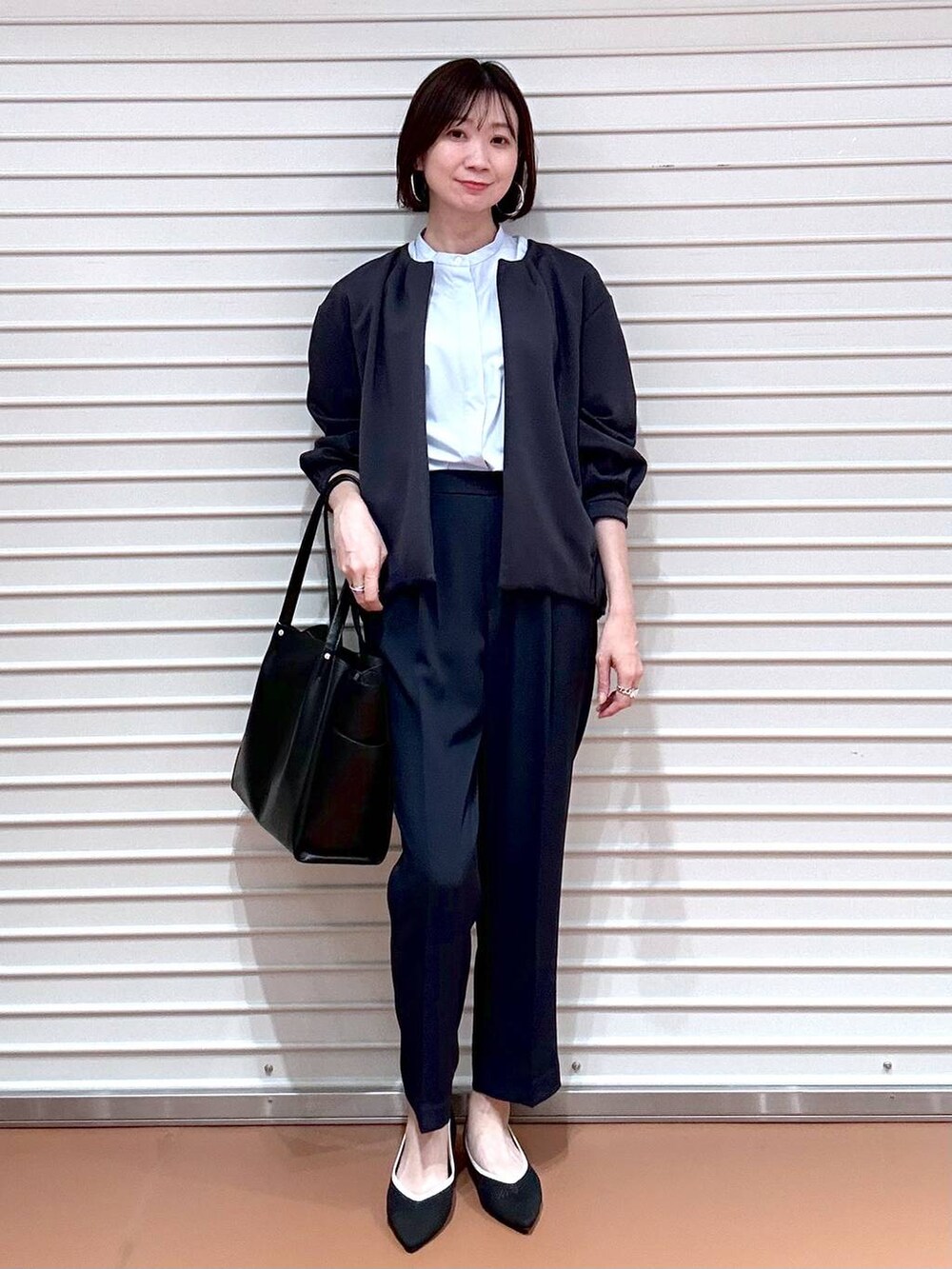 ブラック系のパンプス、ブラック系のトートバッグ、ブルー系のその他パンツを着用したレディースの春コーディネートの2枚目の写真
