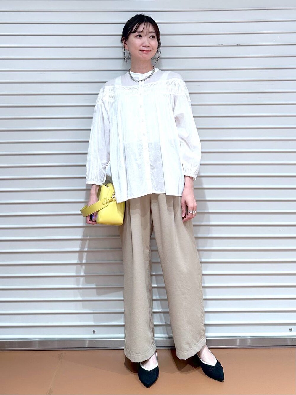 ブラック系のパンプス、ベージュ系のその他パンツ、イエロー系のハンドバッグを着用したレディースの春コーディネートの2枚目の写真