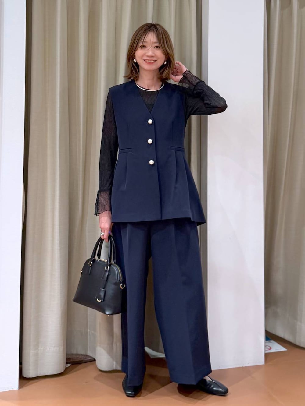 ブラック系のハンドバッグ、ブラック系のパンプス、ブラック系のTシャツ/カットソーを着用したレディースの冬コーディネートの2枚目の写真