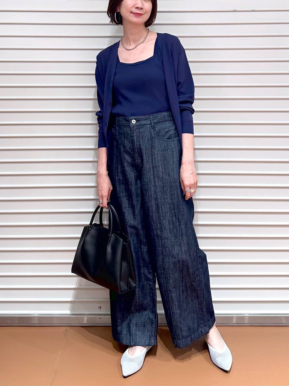 シルバー系のパンプス、ブルー系のデニムパンツ、ブラック系のショルダーバッグを着用したレディースの夏コーディネートの5枚目の写真