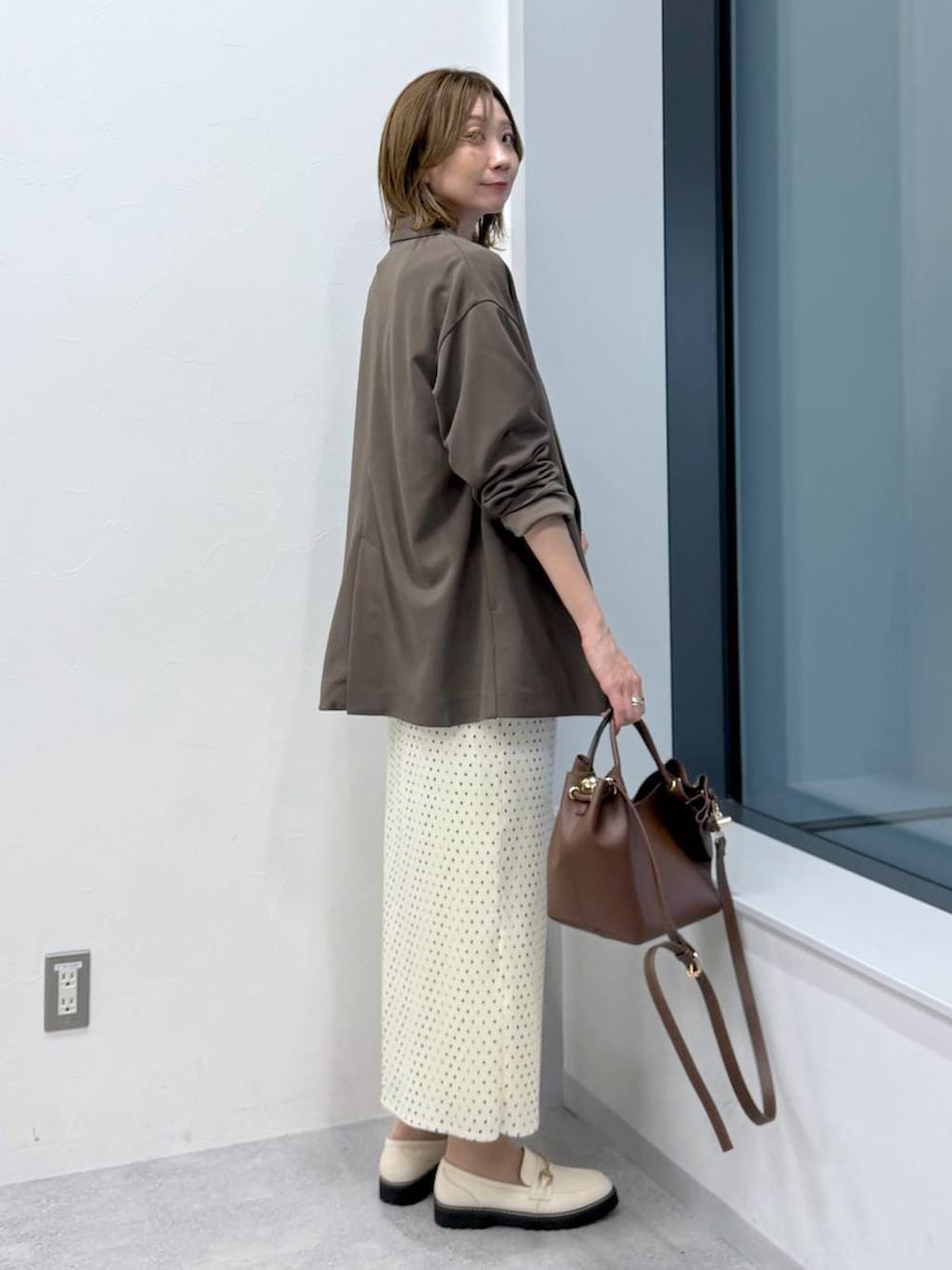 ホワイト系のスカート、ホワイト系のローファー、ホワイト系のTシャツ/カットソーを着用したレディースの冬コーディネートの5枚目の写真