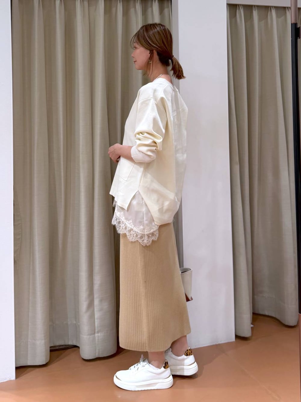 ホワイト系のカーディガン/ボレロ、ベージュ系のスカート、ホワイト系のキャミソールを着用したレディースの冬コーディネートの6枚目の写真
