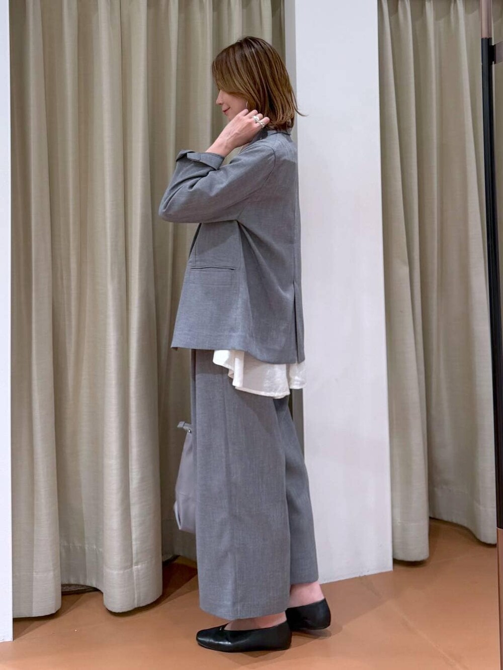 グレー系のトートバッグ、ブラック系のパンプス、ホワイト系のシャツ/ブラウスを着用したレディースの春コーディネートの3枚目の写真