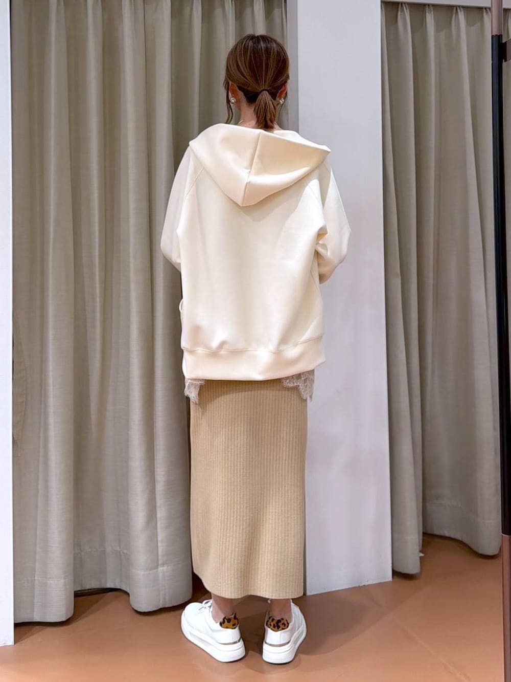 ホワイト系のハンドバッグ、ベージュ系のスカート、ホワイト系のパーカーを着用したレディースの冬コーディネートの4枚目の写真