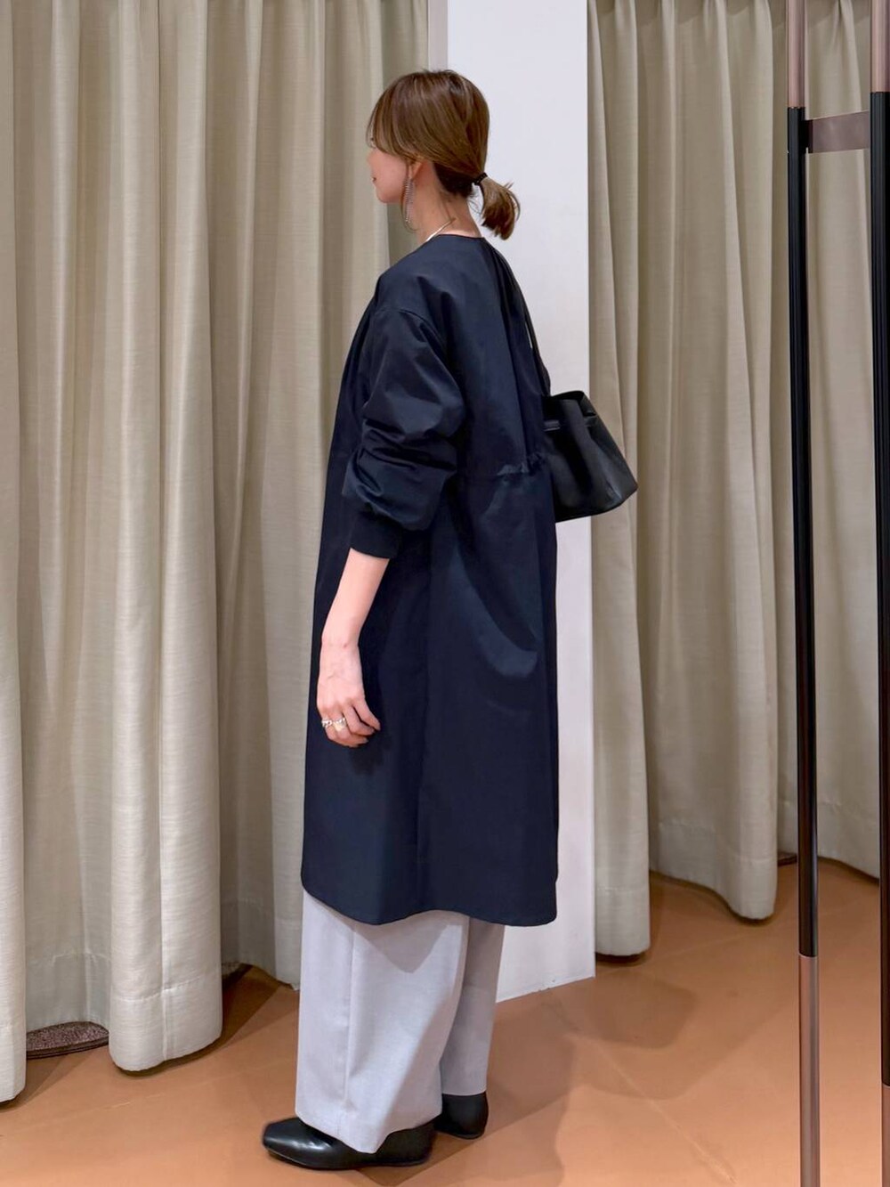 ホワイト系のニット/セーター、ブラック系のパンプス、ブルー系のノーカラーコートを着用したレディースの春コーディネートの3枚目の写真