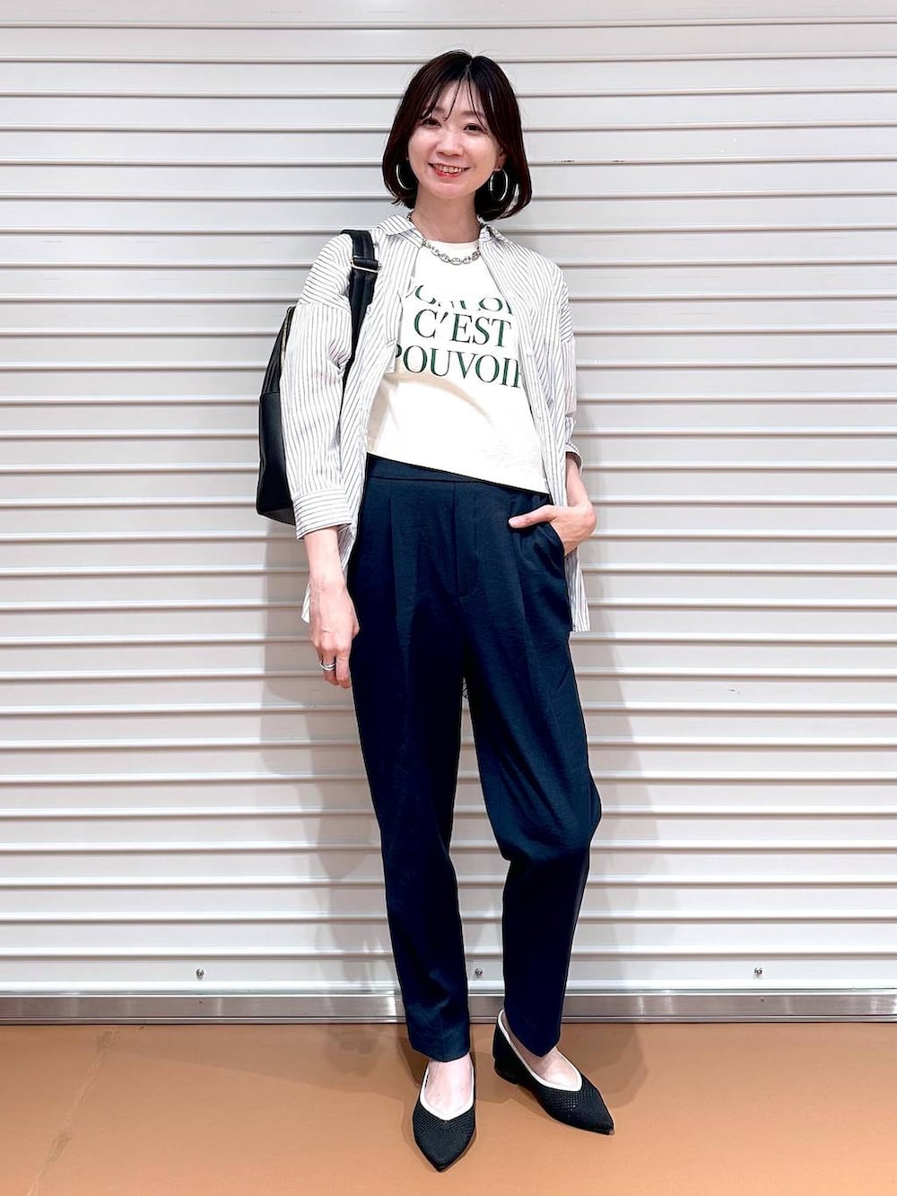 ブラック系のパンプス、ホワイト系のシャツ/ブラウス、ブラック系のバックパック/リュックを着用したレディースの春コーディネートの2枚目の写真