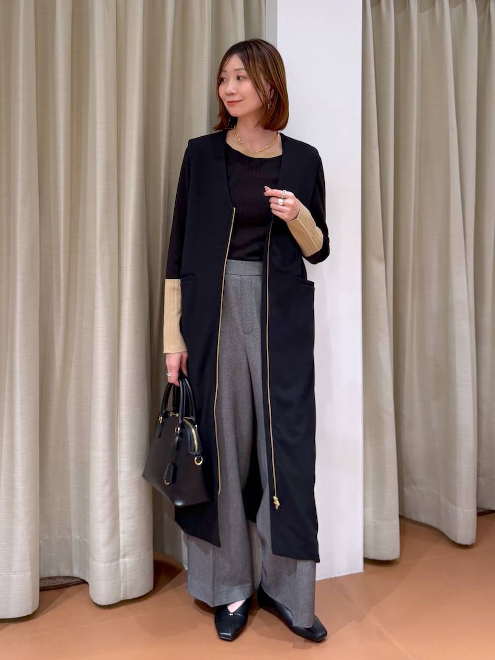 ブラック系のハンドバッグ、グレー系のその他パンツ、ブラック系のパンプスを着用したレディースの冬コーディネートの6枚目の写真