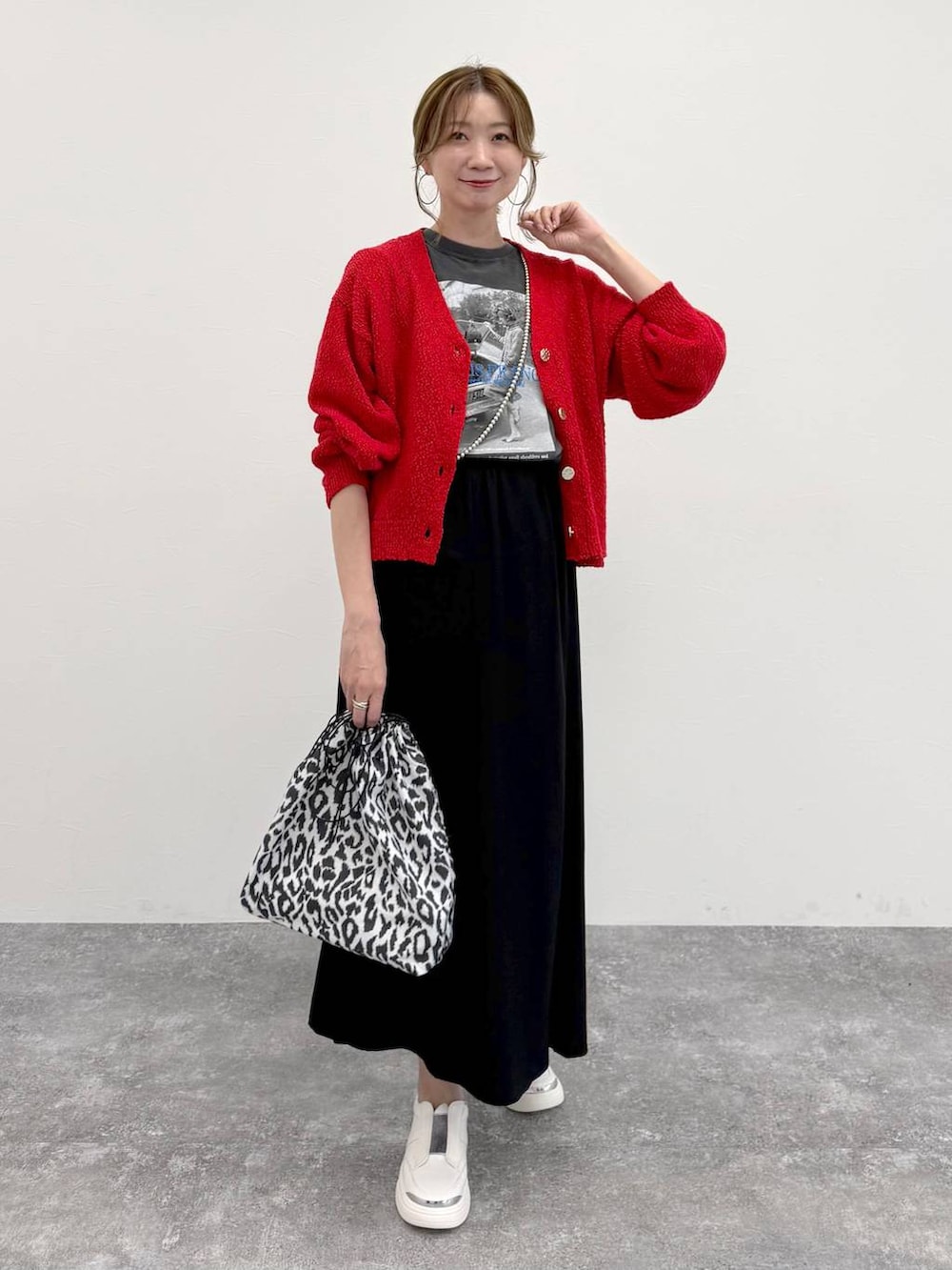 シルバー系のスニーカー、ブラック系のスカート、レッド系のカーディガン/ボレロを着用したレディースの春コーディネートの2枚目の写真