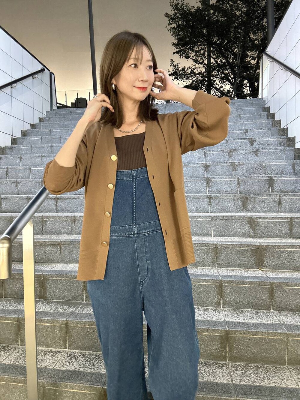 ブラウン系のニット/セーター、ブラウン系のカーディガン/ボレロ、ブルー系のサロペット/オーバーオールを着用したレディースの夏コーディネートの3枚目の写真