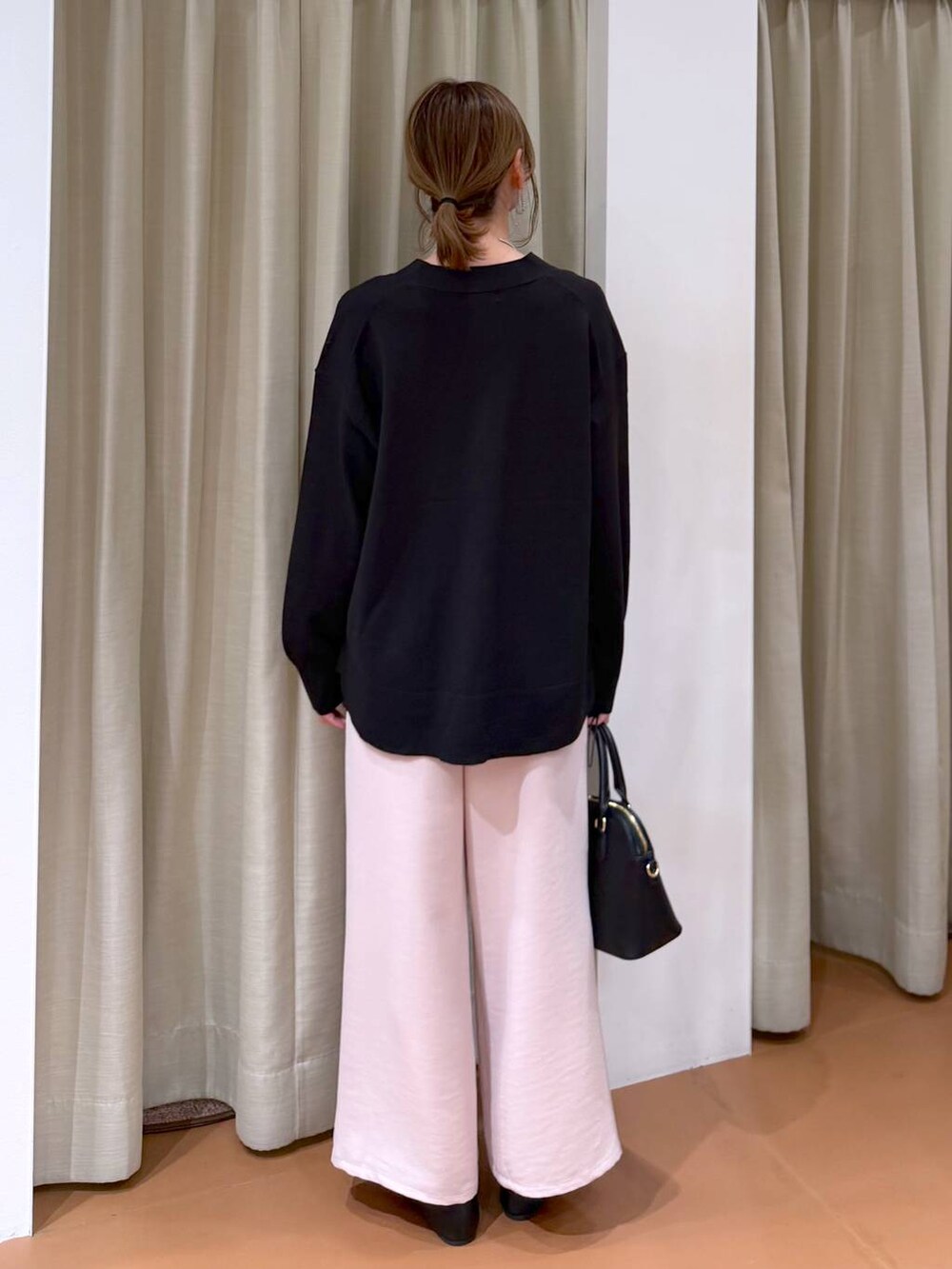 ブラック系のハンドバッグ、ブラック系のパンプス、ブラック系のタンクトップを着用したレディースの冬コーディネートの4枚目の写真