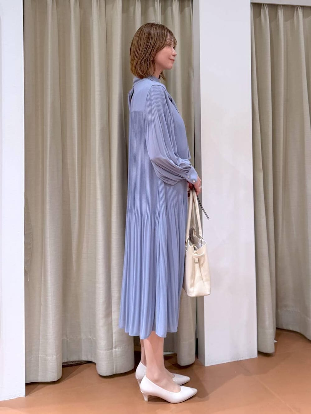 ベージュ系のパンプス、ブルー系のワンピース、ホワイト系のハンドバッグを着用したレディースの冬コーディネートの5枚目の写真