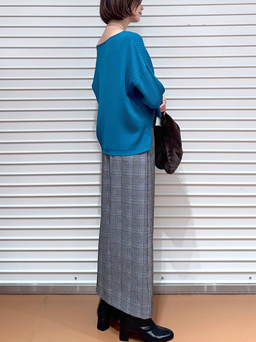 ブラック系のスカート、ブルー系のニット/セーター、シルバー系のネックレスを着用したレディースの秋コーディネートの6枚目の写真