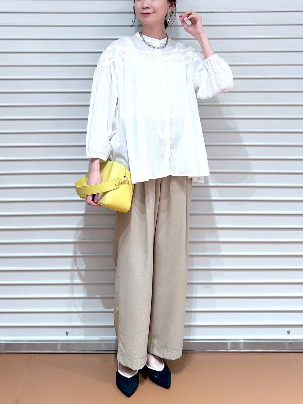 ブラック系のパンプス、ベージュ系のその他パンツ、イエロー系のハンドバッグを着用したレディースの春コーディネートの5枚目の写真