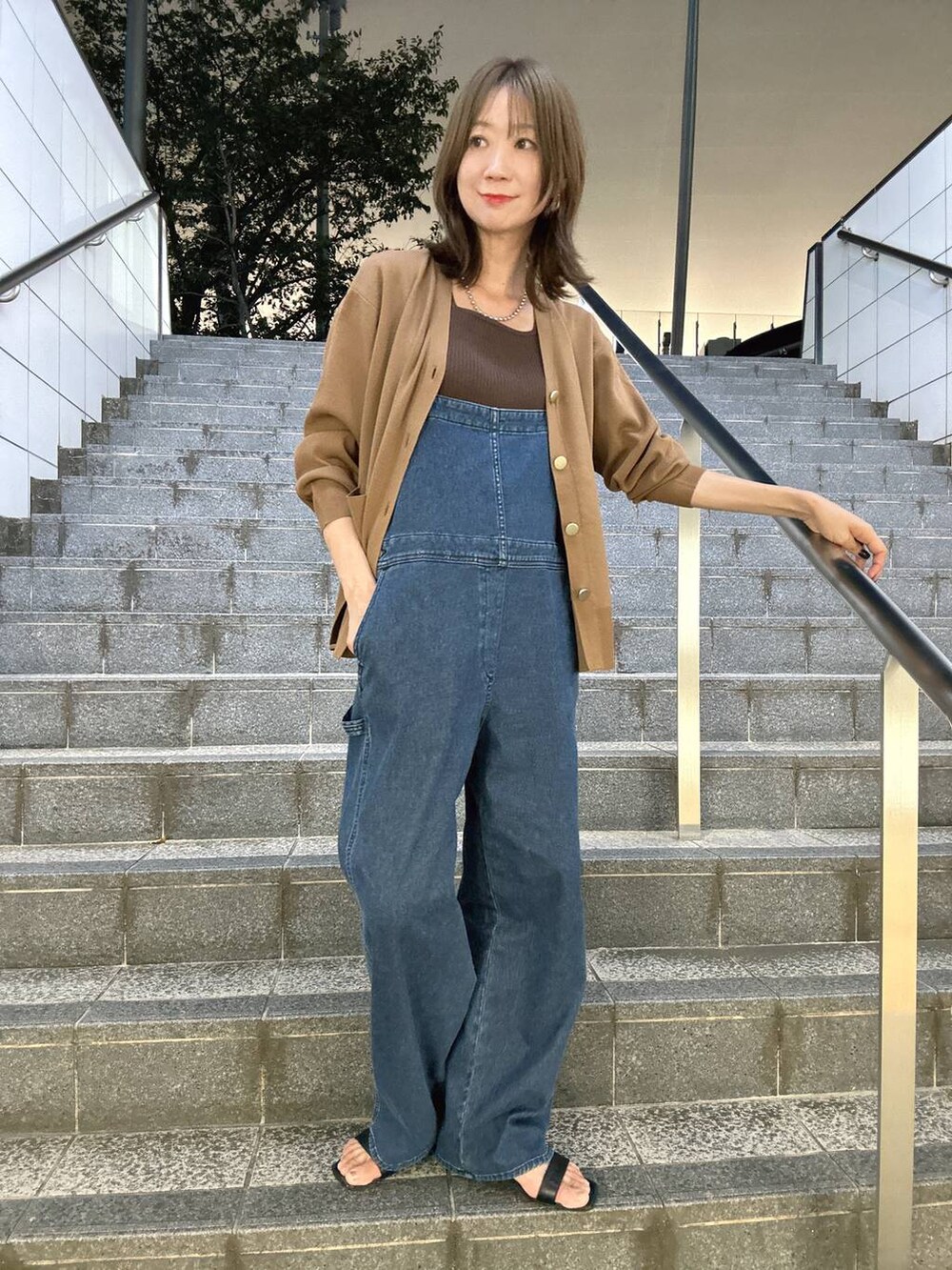 ブラウン系のニット/セーター、ブラウン系のカーディガン/ボレロ、ブルー系のサロペット/オーバーオールを着用したレディースの夏コーディネートの5枚目の写真