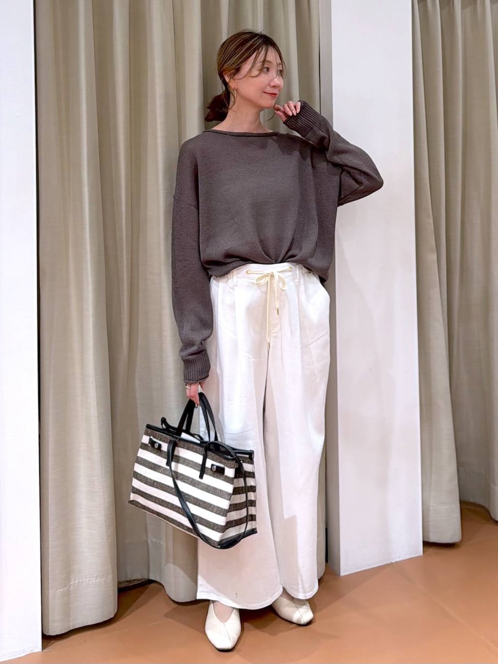 ホワイト系のパンプス、ホワイト系のデニムパンツ、ブラック系のトートバッグを着用したレディースの春コーディネートの2枚目の写真