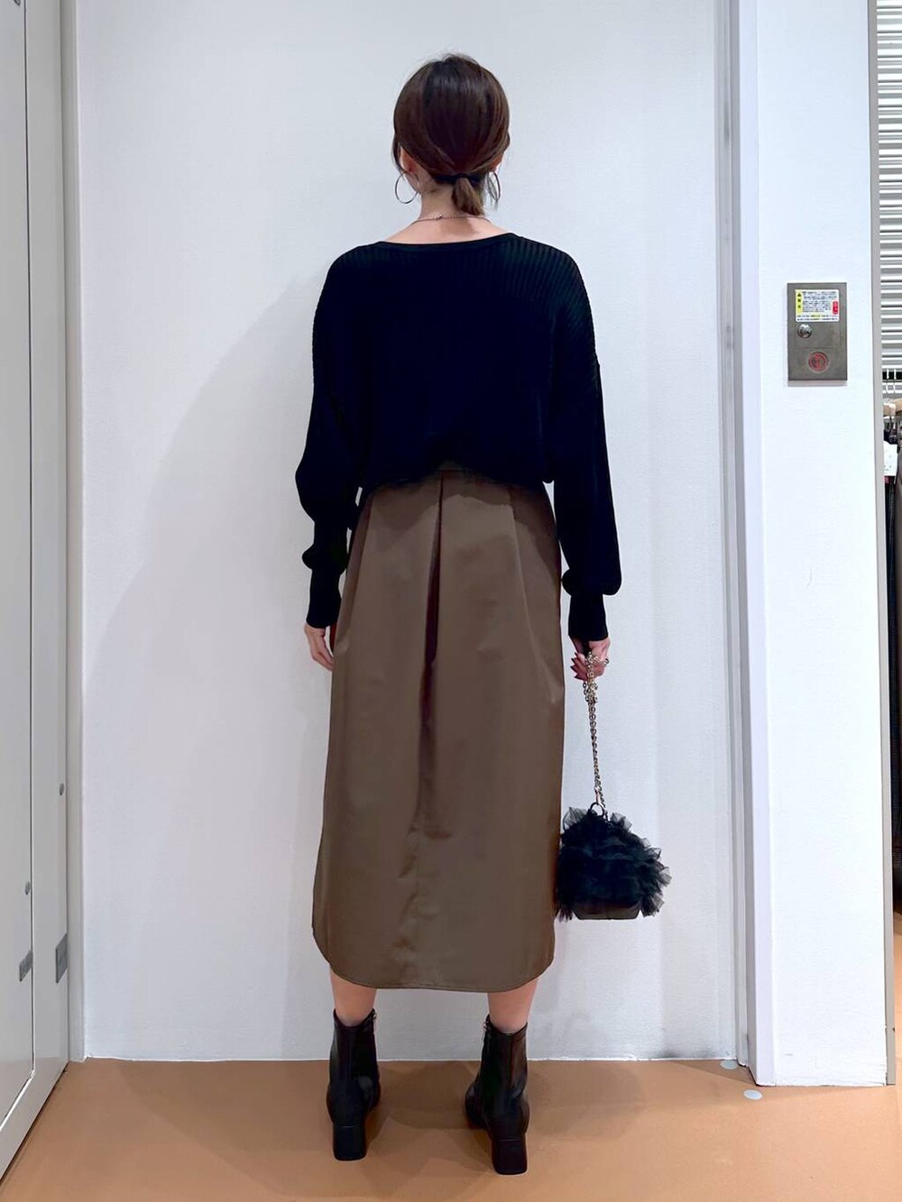 ブラック系のカーディガン/ボレロ、ブラウン系のスカート、ブラック系のブーツを着用したレディースの秋コーディネートの4枚目の写真