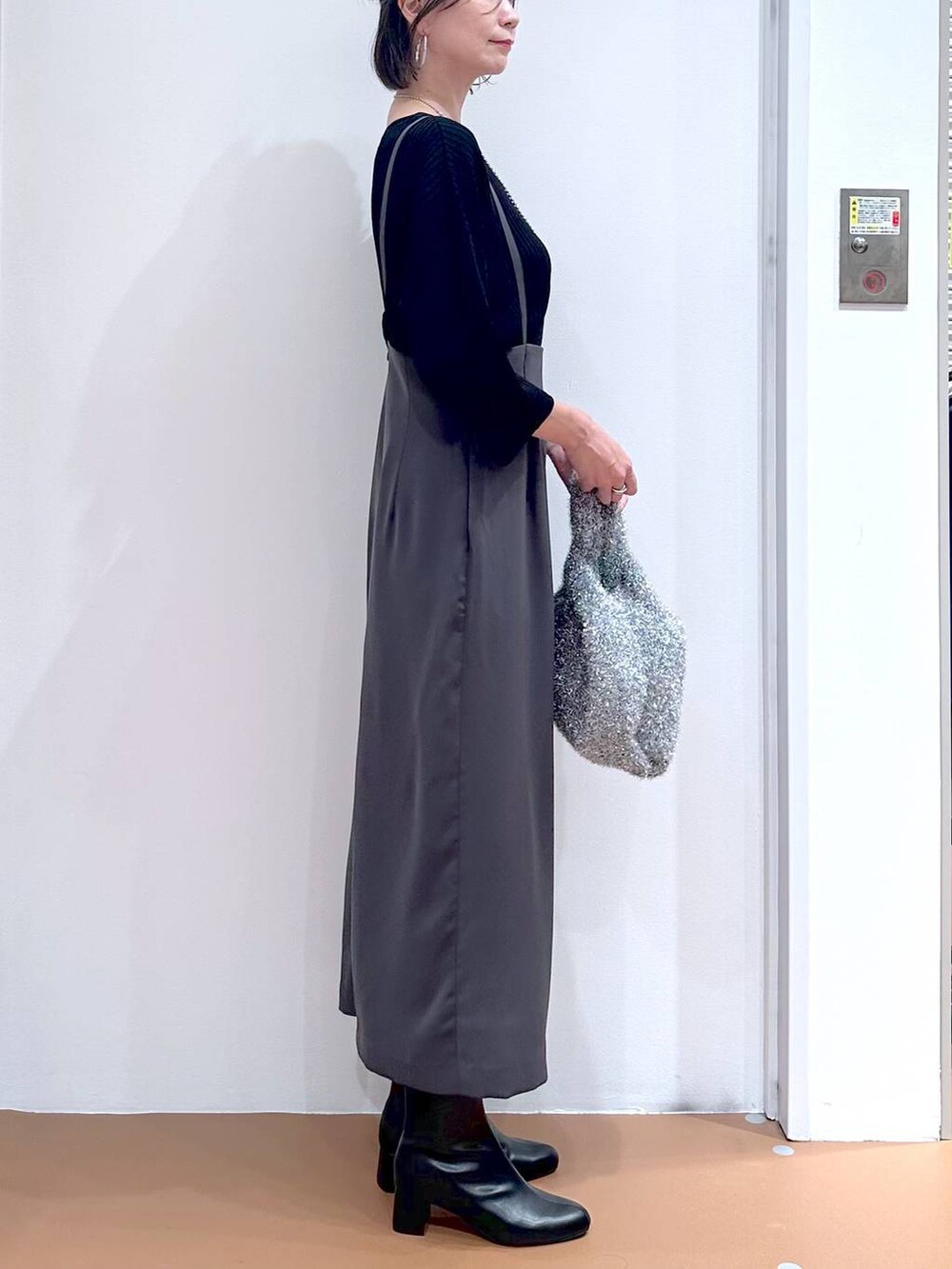 ブラック系のニット/セーター、グレー系のスカート、シルバー系のネックレスを着用したレディースの秋コーディネートの6枚目の写真