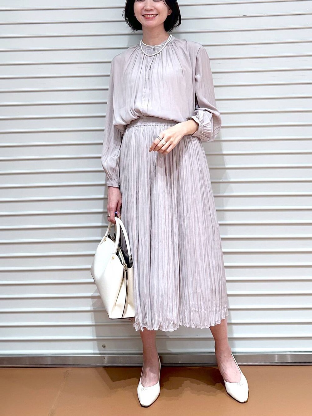 ホワイト系のショルダーバッグ、ピンク系のスカート、ホワイト系のパンプスを着用したレディースの冬コーディネートの4枚目の写真