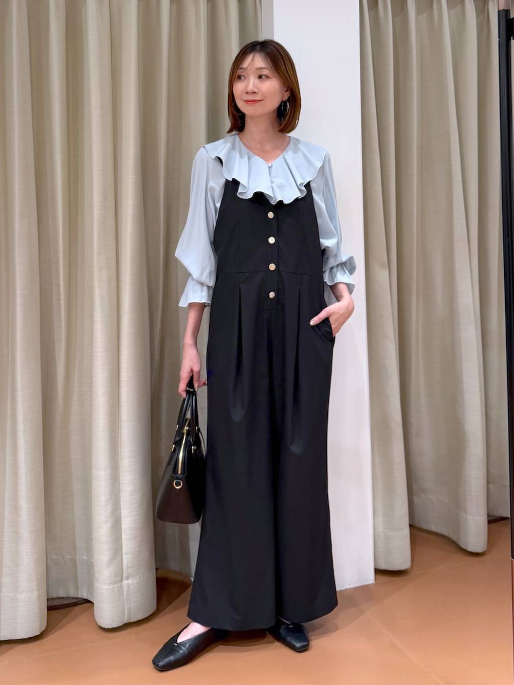 ブラック系のハンドバッグ、ブラック系のパンプス、ブルー系のシャツ/ブラウスを着用したレディースの冬コーディネートの2枚目の写真