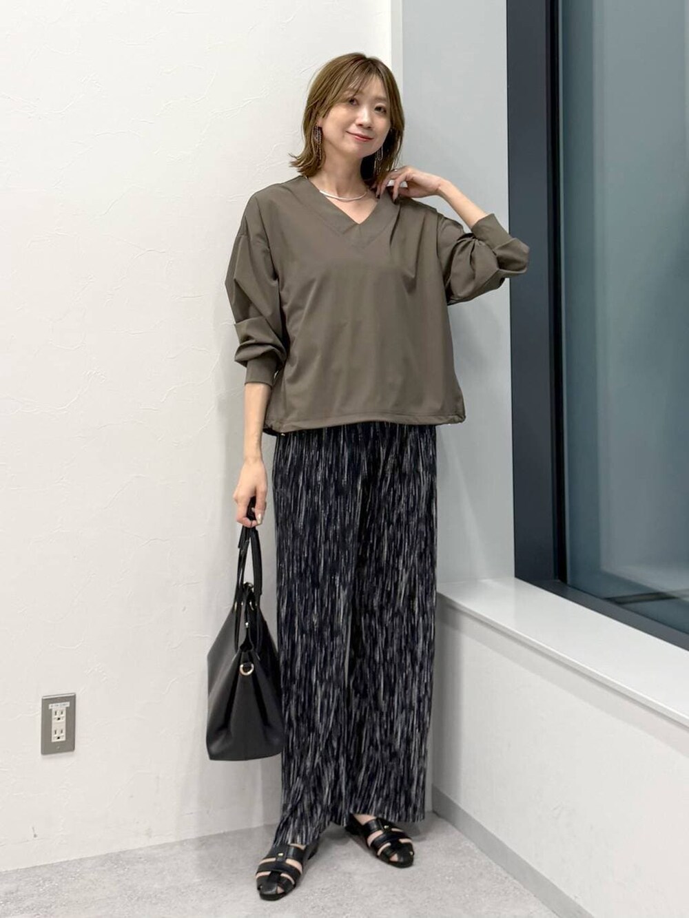 ブラック系のその他パンツ、ブラック系のトートバッグ、グリーン系のTシャツ/カットソーを着用したレディースの冬コーディネートの2枚目の写真