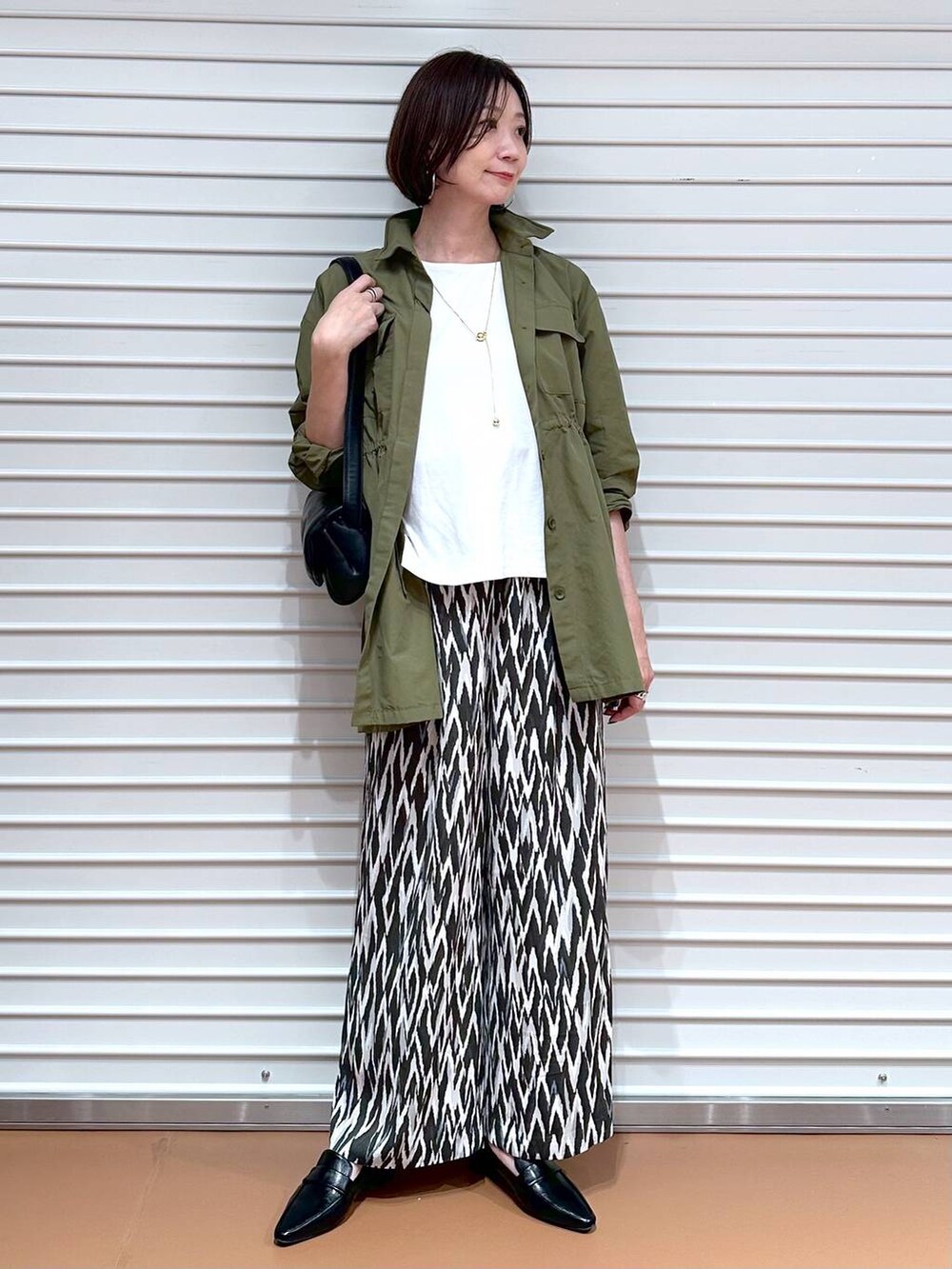 ブラック系のローファー、ホワイト系のTシャツ/カットソー、グリーン系のその他アウターを着用したレディースの秋コーディネートの2枚目の写真