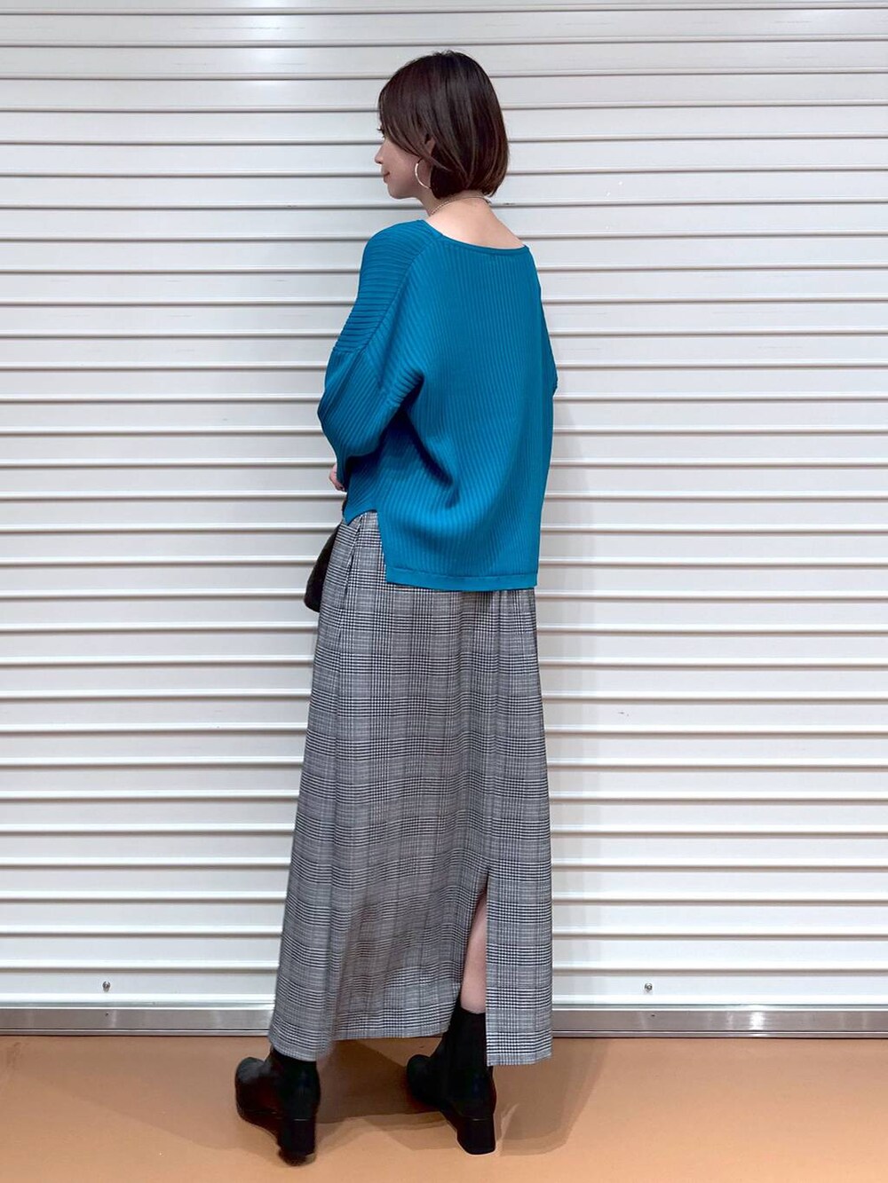 ブラック系のスカート、ブルー系のニット/セーター、シルバー系のネックレスを着用したレディースの秋コーディネートの4枚目の写真